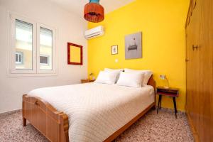 a bedroom with a bed with a yellow wall at Dafni Local Style, 1 Min from Main Beach in Kardamaina