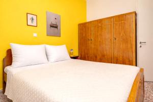 a bedroom with a white bed and a wooden cabinet at Dafni Local Style, 1 Min from Main Beach in Kardamaina