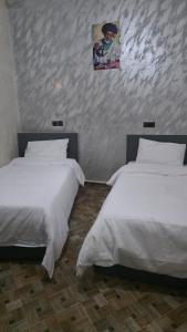 two beds in a room with white sheets at Maison marhaba2 app2 in Inezgane