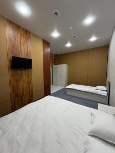 a bedroom with a large white bed and a tv at Shoxdiyor in Angren
