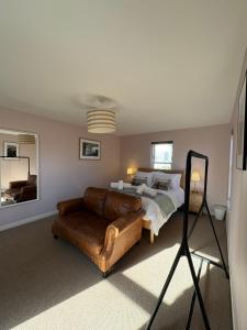 a bedroom with a bed and a leather couch at The Rookery in Orkney