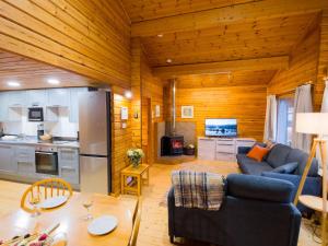 a living room with a blue couch and a kitchen at Tormore Cabin in Carrbridge