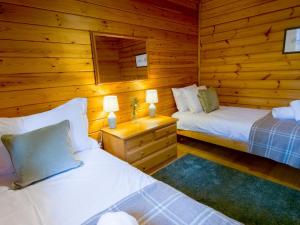 a bedroom with two beds in a log cabin at Tormore Cabin in Carrbridge