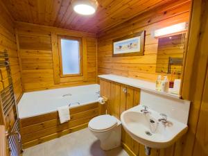 a bathroom with a tub and a toilet and a sink at Tormore Cabin in Carrbridge +19 photos
