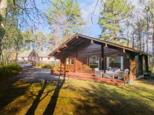 a log cabin with a porch and chairs in the yard at Tormore Cabin in Carrbridge
