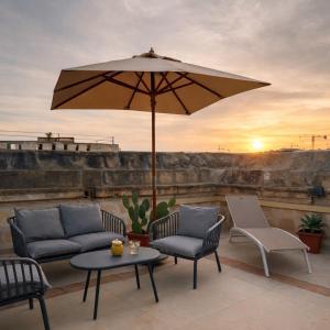 a patio with two chairs and a table and an umbrella at Nelsonhaus -Boutique Guesthouse in Cospicua