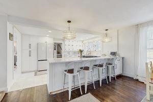 a kitchen with white cabinets and a bar with stools at The Hilltop - Main House in Waterbury
