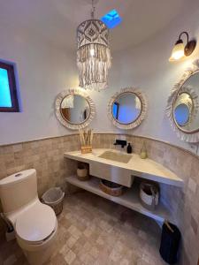 a bathroom with a toilet and three mirrors at Tierra Alta Boho House in San Miguel de Allende