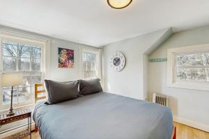 a bedroom with a large bed and two windows at The Hilltop - Main House in Waterbury