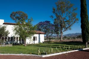 a white house with trees in the foreground at Tierra Alta Boho House in San Miguel de Allende