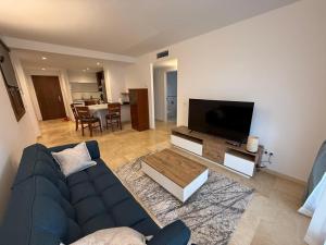 a living room with a blue couch and a flat screen tv at Tus vacaciones junto al mar in Torrevieja