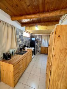 a kitchen with wooden cabinets and a sink and a stove at Cielo Azul 4 in Villa Pehuenia