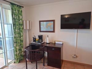 a room with a desk with a television on the wall at Hibiscus 972 in Sainte-Luce