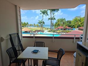 a table and chairs with a view of the pool at Hibiscus 972 in Sainte-Luce