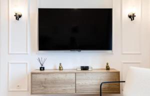 a flat screen tv on a wall with a wooden dresser at MONTE CARLO BORDER - exclusive & modern flat in Beausoleil