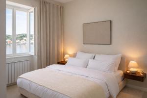 a bedroom with a large white bed with two lamps at The Wave Seafront Apartment Vis in Vis