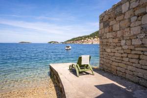 a green chair sitting on a wall next to the water at The Wave Seafront Apartment Vis in Vis
