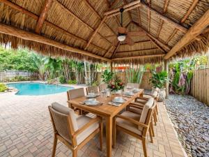 an outdoor dining room with a wooden table and chairs at Hidden Gem Vacation Villa w Private Pool & TikiHut in Fort Lauderdale