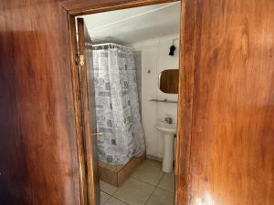 a bathroom with a shower curtain and a sink at Hostal Vaihere in Hanga Roa
