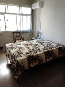 a bedroom with a bed and a chair and a window at Quarto no apartamento do anfitrião na Praia do Canto in Vitória