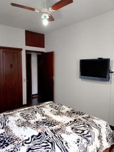 a bedroom with a bed and a ceiling fan at Quarto no apartamento do anfitrião na Praia do Canto in Vitória