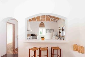 a kitchen with white walls and a counter with stools at Monte das Oliveiras - Casas de Campo in Estremoz