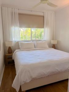 a bedroom with a large white bed with a window at Tropic Sands Coastal Escape in Port Douglas