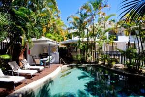 a swimming pool in a yard with chairs and trees at Tropic Sands Coastal Escape in Port Douglas