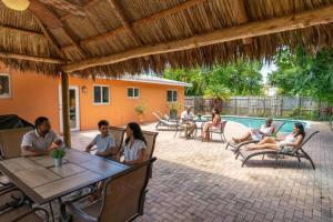 a group of people sitting around a patio with a pool at Hidden Gem Vacation Villa w Private Pool & TikiHut in Fort Lauderdale