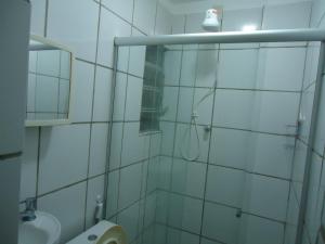 a white tiled bathroom with a shower and a sink at Pousada Popular in Três Marias +8 photos