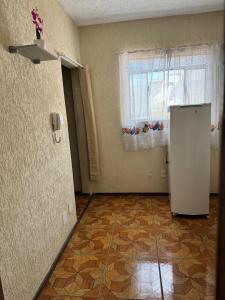 an empty room with a refrigerator and a window at Pousada Popular in Três Marias