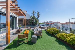 a patio with a lawn with chairs and tables at Ericeira Ocean View Villa in Ericeira