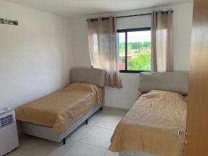 a small bedroom with two beds and a window at Casa Ville Perignon in Gravatá