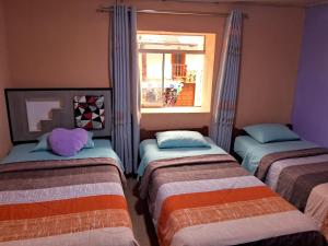 three beds in a room with a window at Hospedaje Don Pepe in Churín