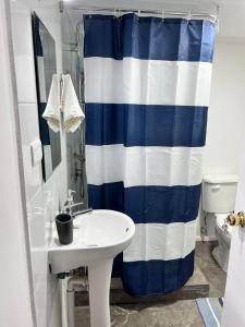 a bathroom with a sink and a blue and white shower curtain at Cabaña Centro in Coihaique