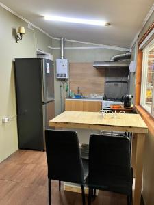 a kitchen with a table and two chairs and a refrigerator at Cabaña Centro in Coihaique