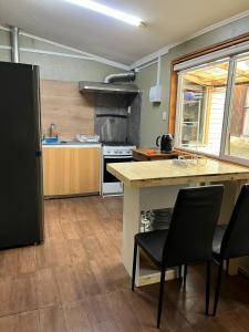 a kitchen with a counter and some chairs in it at Cabaña Centro in Coihaique +2 photos