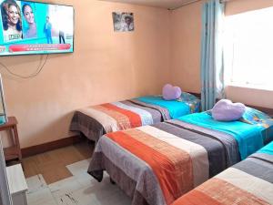 two beds in a room with a tv on the wall at Hospedaje Don Pepe in Churín +11 photos