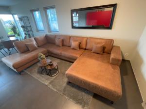 a living room with a brown couch and a table at Le Daguet pour 8 in Florenville