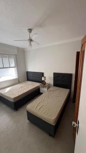 a bedroom with two beds and a ceiling fan at Apê Completo - 300m da Praia in Guarujá