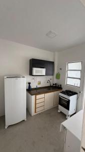 a kitchen with a white refrigerator and a stove at Apê Completo - 300m da Praia in Guarujá