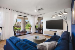a living room with a blue couch and a tv at New Sunset Villa Ocean Side Lanai Pool Kings in Waikoloa