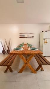 a wooden table with plates on it in a room with a refrigerator at Espaço Move in Porto Seguro