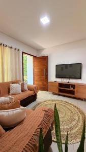 a living room with two couches and a flat screen tv at Espaço Move in Porto Seguro