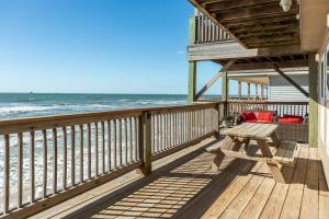 a wooden deck with a table and chairs on the beach at Paradise Point - Barefoot Beachfront Living in Surfside Beach