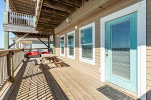 a wooden porch with a picnic table and a balcony at Paradise Point - Barefoot Beachfront Living in Surfside Beach