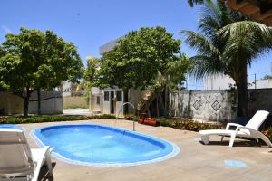 a swimming pool in a yard with chairs and a house at Pousada Bem-te-vi in Aracaju