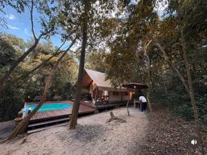 a person standing in front of a house in the woods at Bandu Buana Glamping in Kuala Pilah