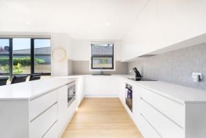 a white kitchen with white counter tops and windows at Mid-Century Home Near Hospital and Woden - Hosted by Canstay in Phillip