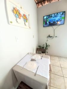 a white table in a room with a tv on the wall at Pousada Aconchego em Mundaú in Trairi